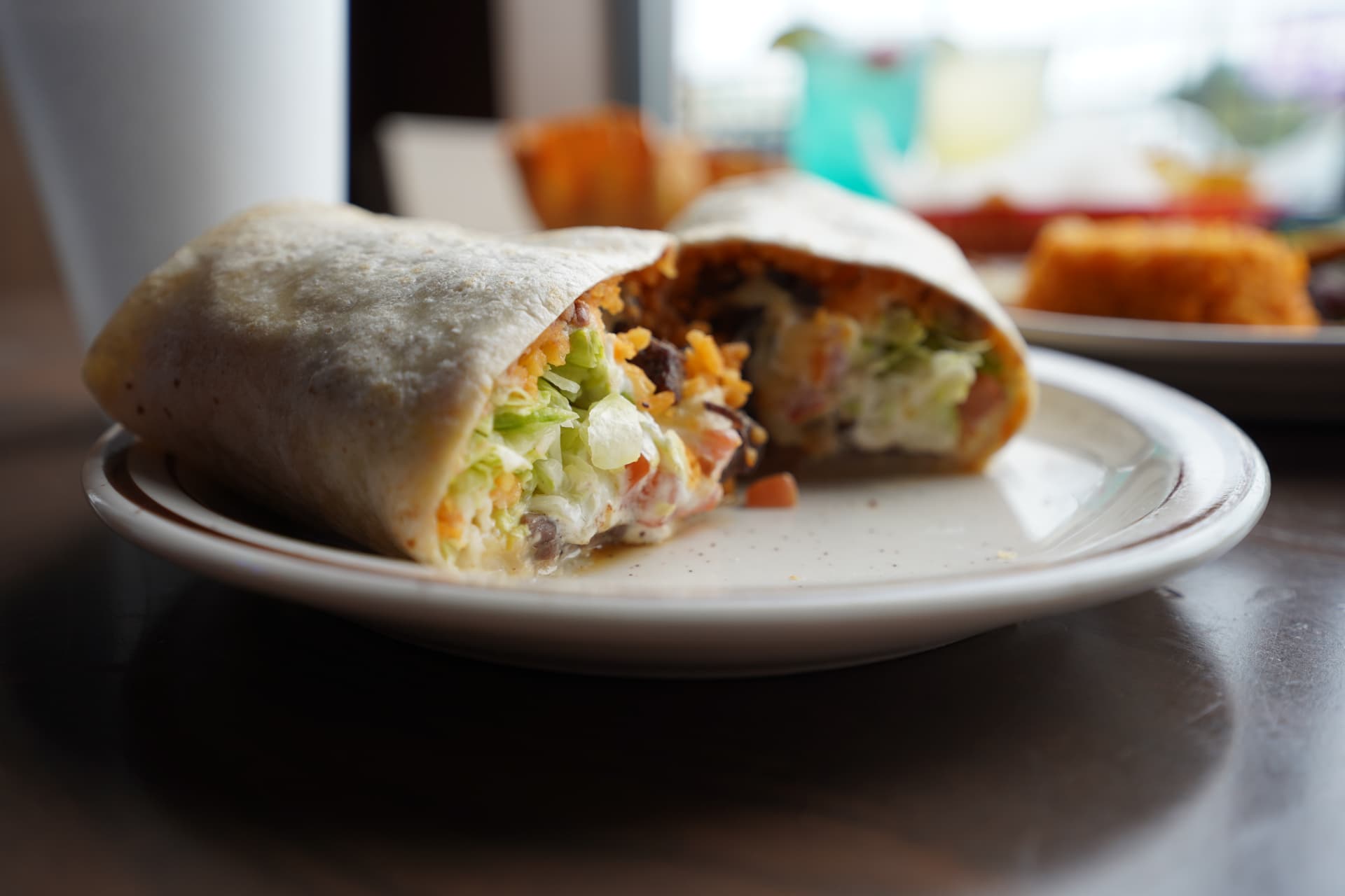 Fresh burrito cut open to show steak, rice, lettuce, tomato, and crema