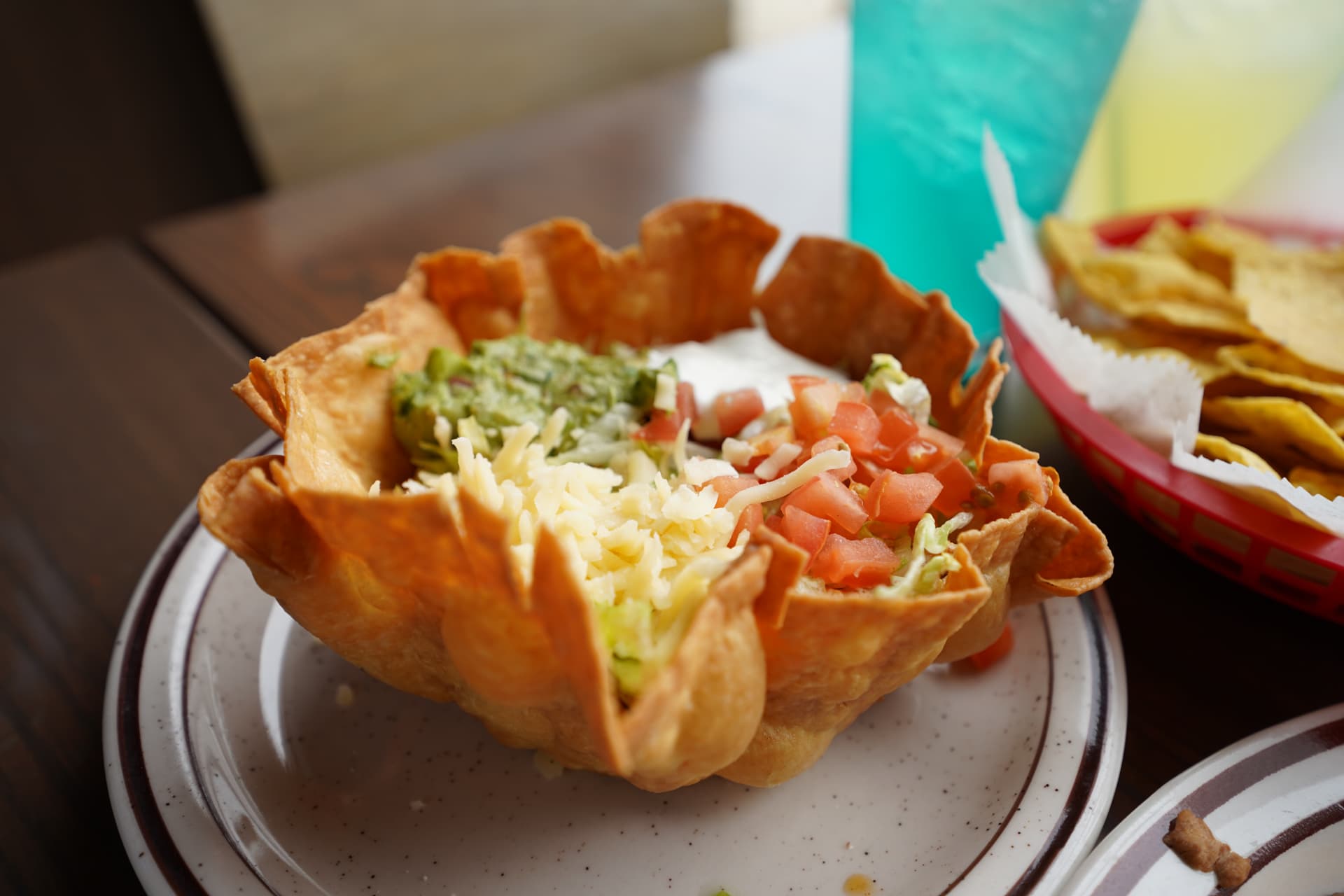 Taco salad in a crisp tortilla bowl with guacamole and fresh toppings